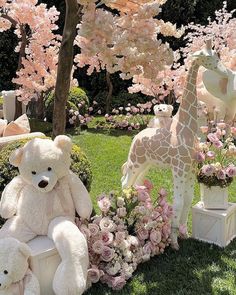 several stuffed animals and flowers on display in the grass near trees with pink flowers around them