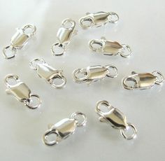 a bunch of silver plated metal clasps on a white table with clipping