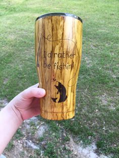 a person holding up a wooden cup with writing on the side and an image of a bear