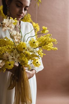 a woman holding a bouquet of yellow and white flowers