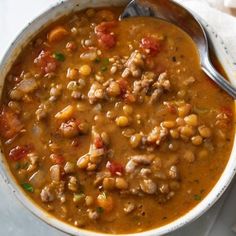 a white bowl filled with beans and meat on top of a table next to a napkin