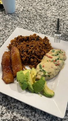 a white plate topped with rice, meat and veggies next to a fork