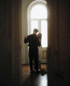 a man and woman standing in front of a window with sunlight coming through the windows