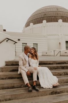 a bride and groom sitting on steps in front of a domed building