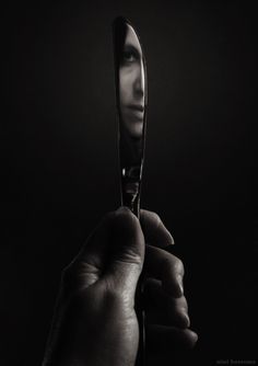 a hand holding a small metal object in black and white with the light shining on it