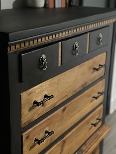 a black dresser with wooden drawers and knobs