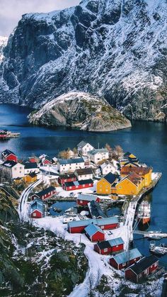 an aerial view of a small town on the water with mountains in the back ground