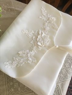 a white pillow with embroidered flowers on it sitting on a lace doily covered tablecloth