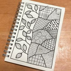 a spiral notebook with an abstract design on the cover, sitting on top of a wooden table