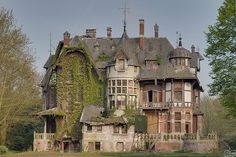 an old house with ivy growing on it's roof and windows in the front