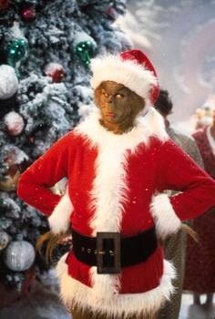 a man dressed as santa clause standing in front of a christmas tree