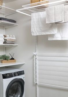 a washer and dryer in a room with white towels hanging on the wall