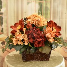 a vase filled with lots of flowers sitting on top of a table next to a window