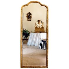 a large mirror sitting on top of a wooden floor next to a table with a black and white striped skirt