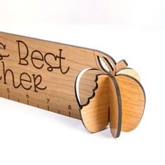 a wooden ruler with an apple on it and the words, the best teacher written in cursive writing