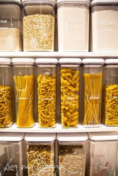 the shelves are filled with different types of pasta in plastic containers and labeled labels on them