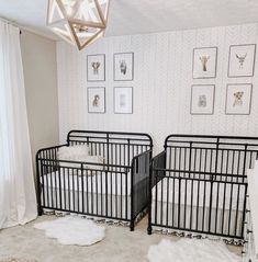 two baby cribs in a white and black nursery with pictures on the wall