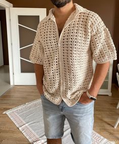 a man standing on top of a wooden floor wearing shorts and a crocheted shirt