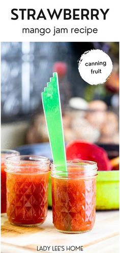 two jars filled with jam sitting on top of a wooden table next to a green plastic straw