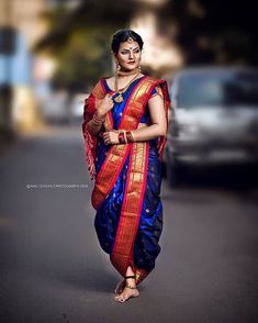 a woman in a blue and red sari walking down the street with her hand on her hip