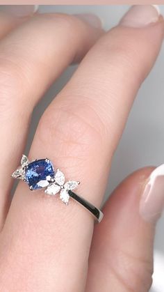 a close up of a person's hand holding a ring with a blue stone