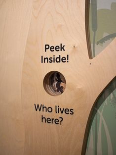 a wooden birdhouse with the words peek inside and who lives here? on it