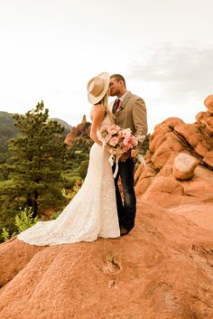 a bride and groom kissing on top of a rock formation in the valley of fire