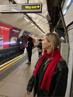 a woman standing in front of a train at a subway station with people waiting on the platform