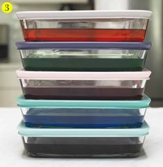 four different colored plastic containers stacked on top of each other in front of an oven