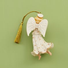 an angel ornament with a tassel hanging from it's side on a green background