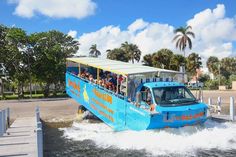 a blue boat with people on it going down the water in front of a dock