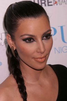 a woman with braid hair and makeup looks into the camera while wearing black dress at an event