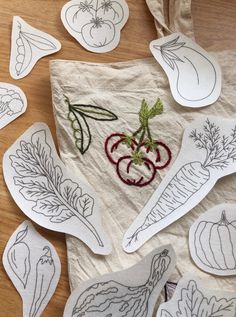 paper cut outs with vegetables on them sitting on top of a wooden table next to scissors