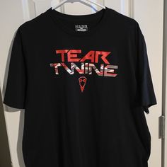 a black t - shirt with the words teak twins on it hanging from a door