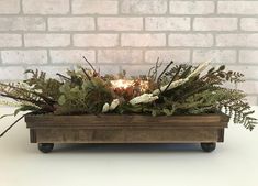 a wooden box filled with greenery and a lit candle