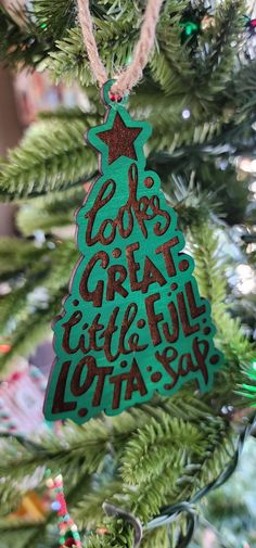 a christmas tree ornament hanging from the top of a fir tree with words on it