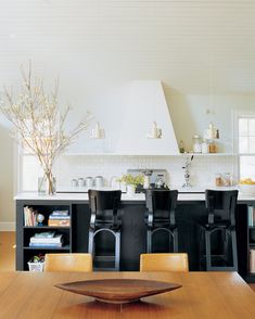 a kitchen with chairs and a table in the center, next to an island that has bookshelves on it