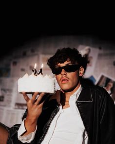 a man in sunglasses holding a cake with candles on it