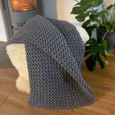 a knitted hat sitting on top of a wooden floor next to a potted plant