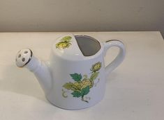 a white tea pot with yellow flowers painted on it