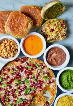 several different types of food are arranged in bowls on a marble countertop, including bread and dips