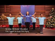 a group of people standing next to each other in front of a christmas tree with their hands up