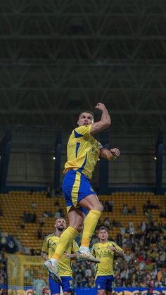 two soccer players jump to head the ball in front of an audience at a sporting event