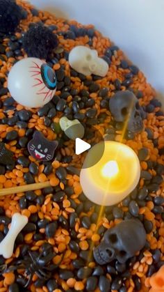 a bowl filled with lots of halloween decorations on top of it's side and a candle in the middle