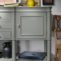 a gray cabinet with drawers and a yellow vase on top