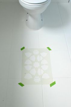 a white toilet sitting on top of a bathroom floor next to a green sticker