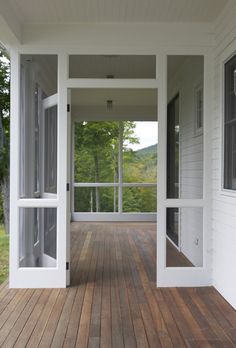 an empty porch with wooden floors and white walls