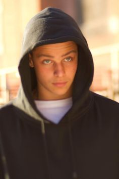 a young man in a black hoodie looking at the camera with an intense look on his face