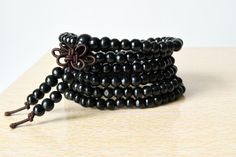 This Mala bracelet is made with high quality 6 mm sandalwood and elastic jewelry cord (216beads).Buddhist prayer beads or Mala are a traditional tool used to count the number of times a mantra is recited, breaths while meditating, counting prostrations, or the repetitions of a Buddha's name. They are similar to other forms of prayer beads used in various world religions and therefore the term "Buddhist rosary" also appears.When reciting a mantra with a Mala meditation, you recite the entire mant Traditional Black Bracelets With Wooden Beads, Traditional Black Bracelet With Wooden Beads, Black Wooden Beads Bracelet For Gift, Black Wooden Beaded Bracelets, Black Bracelet With 108 Beads, Black Wooden Beads Bracelets For Meditation, Black Wooden Beads Bracelet As Gift, Black Wooden Beaded Bracelets Gift, Traditional Black Wooden Beaded Bracelets