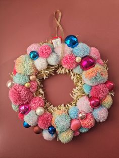 a multicolored pom - pom wreath hanging on a wall with other ornaments